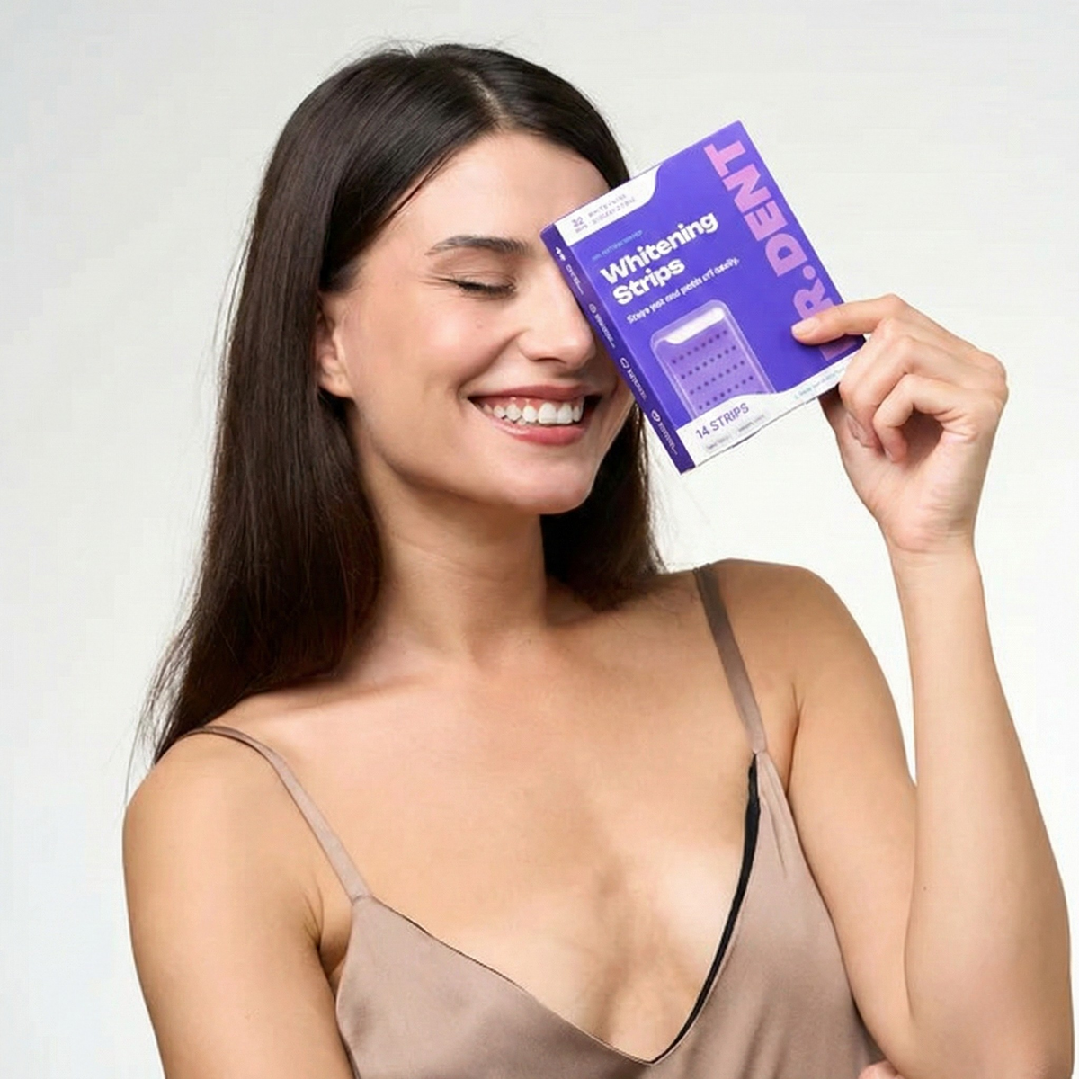 Vrouw houdt Dr. Dent Whitening Strips doosje voor haar oog